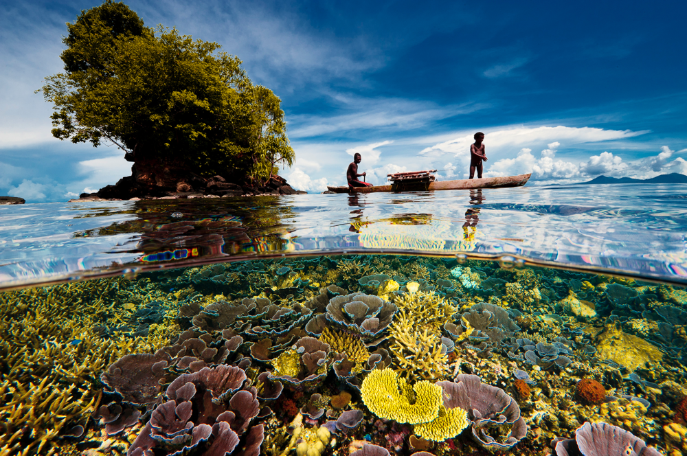 Halb- und Halbbild eines einheimischen Fischers mit jungem Sohn in einem Auslegerboot aus einem Dorf auf der Willaumez-Halbinsel auf der Insel New Britain, Kimbe Bay, Papua-Neuguinea. Agenda 2030: Meere nachhaltig nutzen