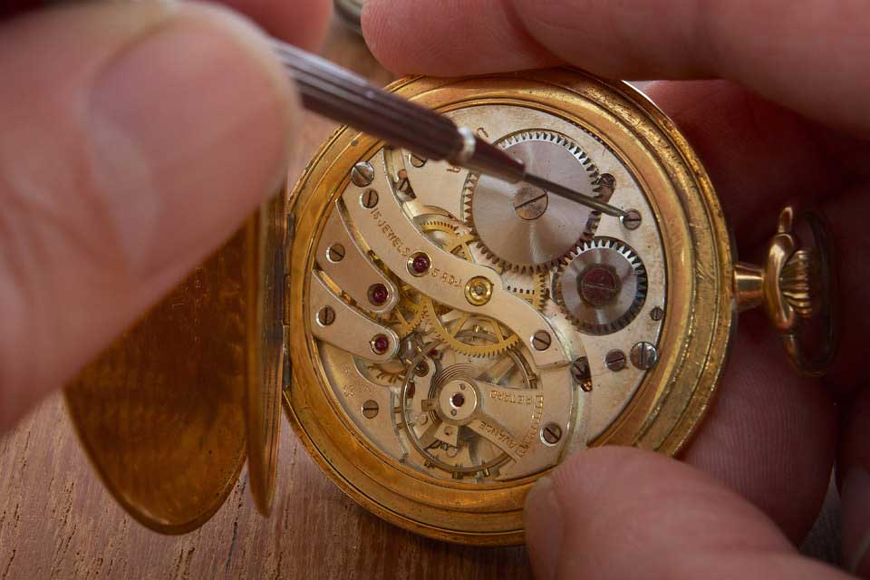 hands that repair an old pocket watch