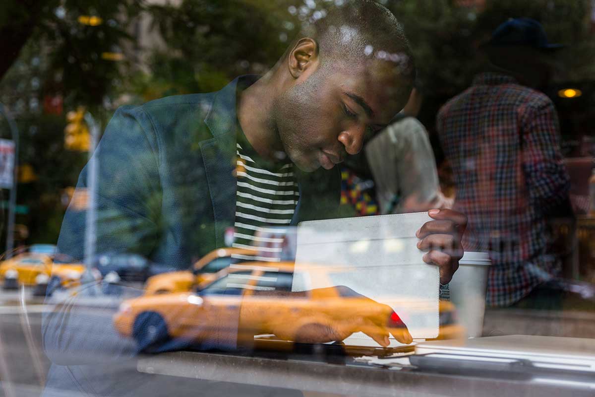 Young Black Man with Digital Tablet in a Cafe